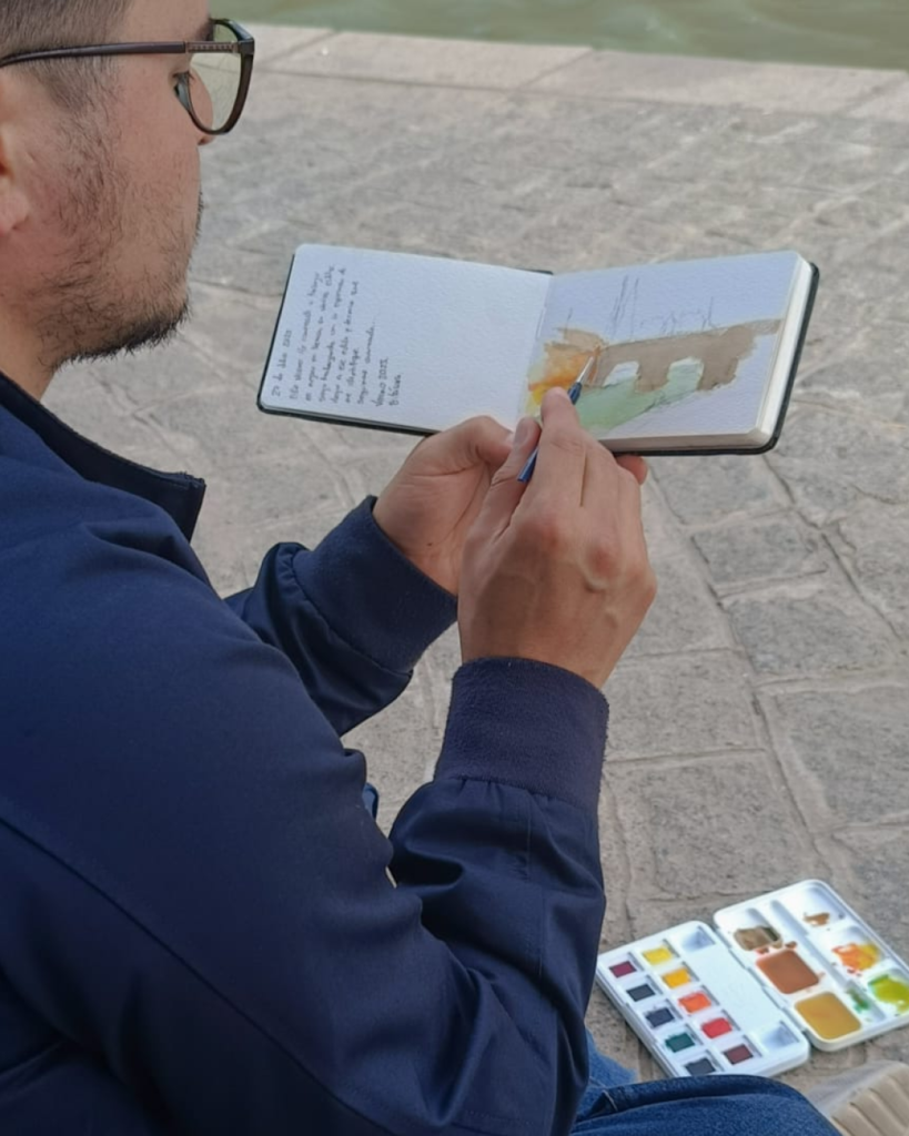 Yohan Pixone pintando con acuarela al aire libre como parte de su proceso artístico de observación del espacio.