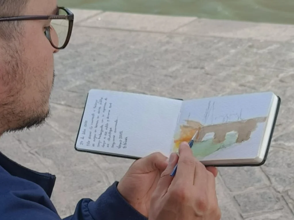 Yohan Pixone pintando con acuarela al aire libre como parte de su proceso artístico de observación del espacio.