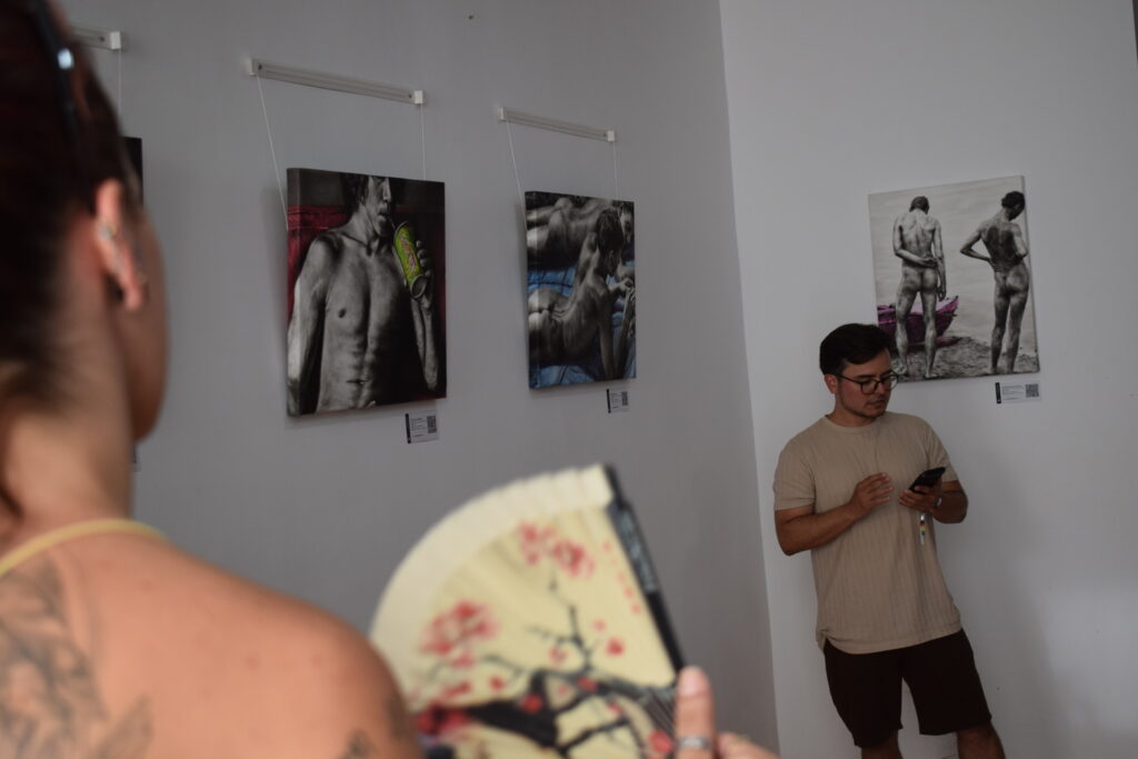 Visitantes conversando frente a las pinturas de Cuerpos en suspensión de Yohan Pixone.