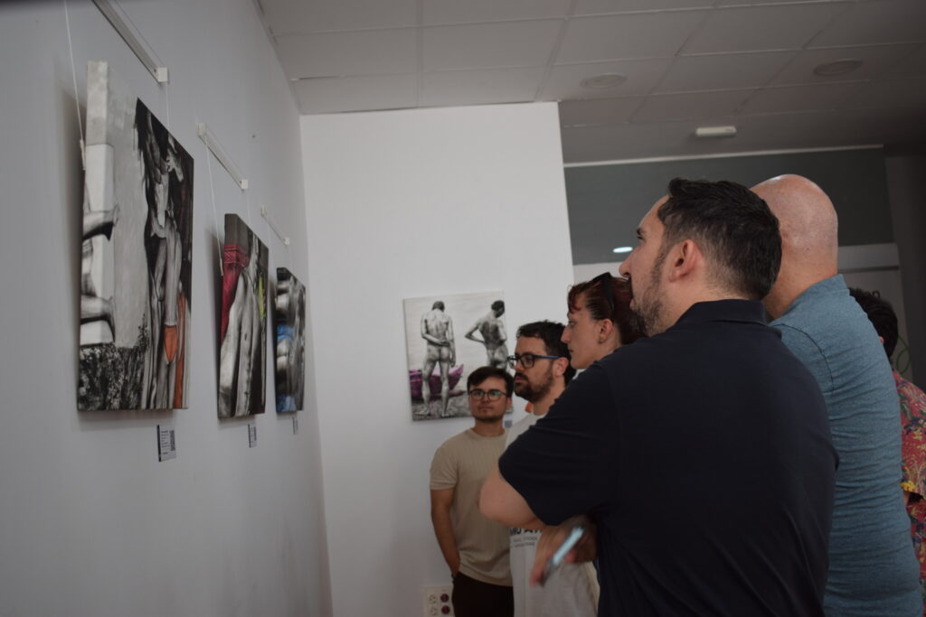 Visitantes conversando frente a las pinturas de Cuerpos en suspensión de Yohan Pixone.
