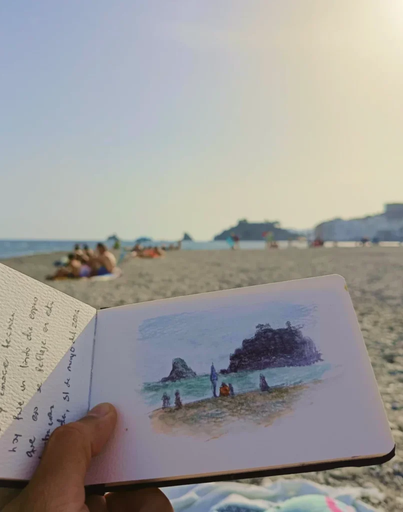 Acuarela de Yohan Pixone realizada en la playa de Almuñécar, con vista del Mediterráneo y figuras frente al mar.
