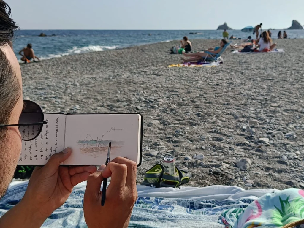 Acuarela de Yohan Pixone realizada en la playa de Almuñécar, con vista del Mediterráneo y figuras frente al mar.