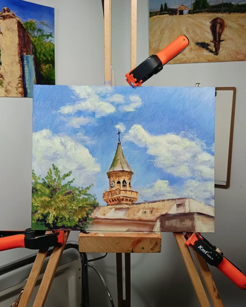 Pintura de paisaje de Las Gabias realizada por Yohan Pixone, con torre de iglesia, cielo azul, nubes y masa vegetal.