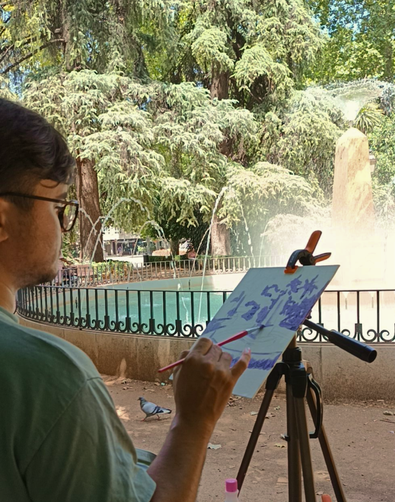 Pintura de Yohan Pixone frente a la fuente y la vegetación que observó durante su segunda salida al aire libre en Granada.